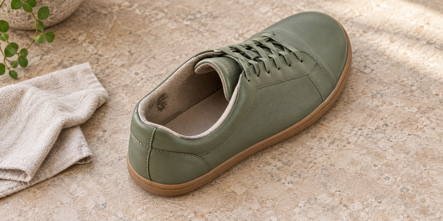 Inside heel of a green leather barefoot sneaker with a small worn lining patch